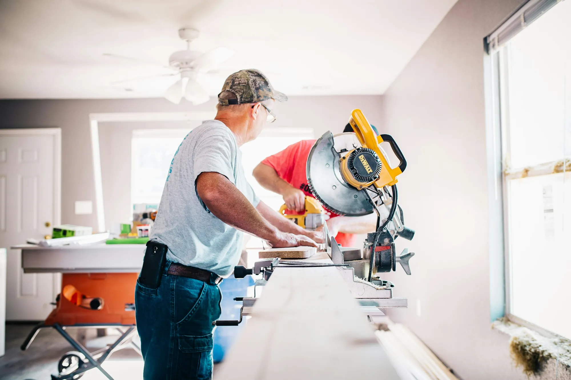 Handyman cutting trim on a miter saw inside a bright home