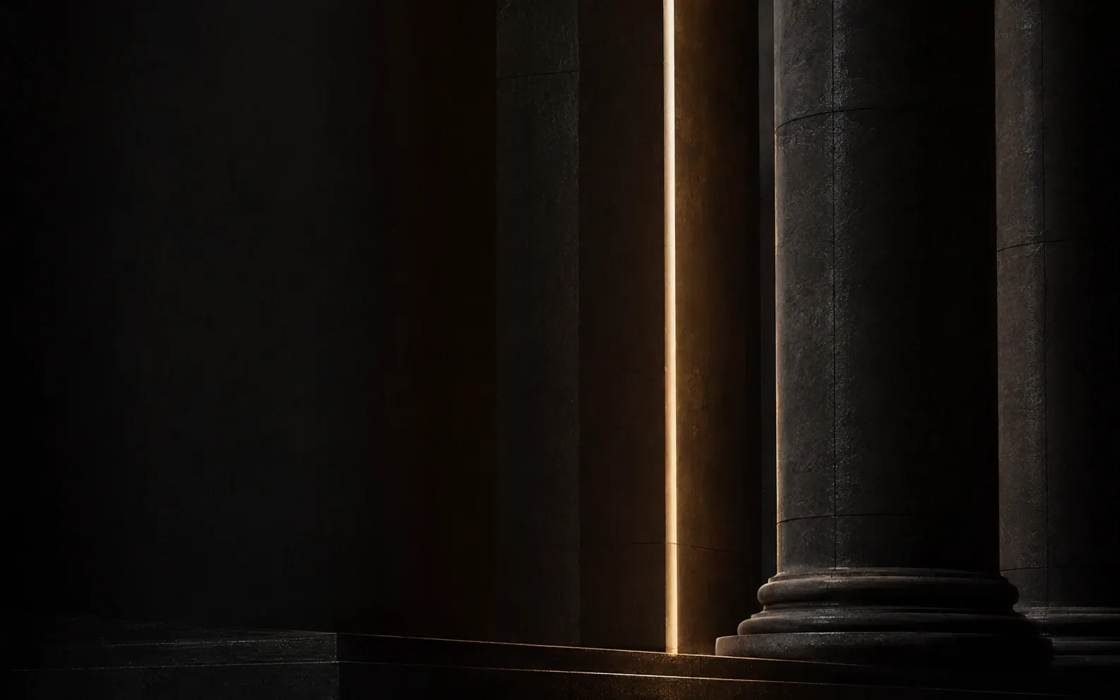 Monumental dark stone columns crossed by warm light
