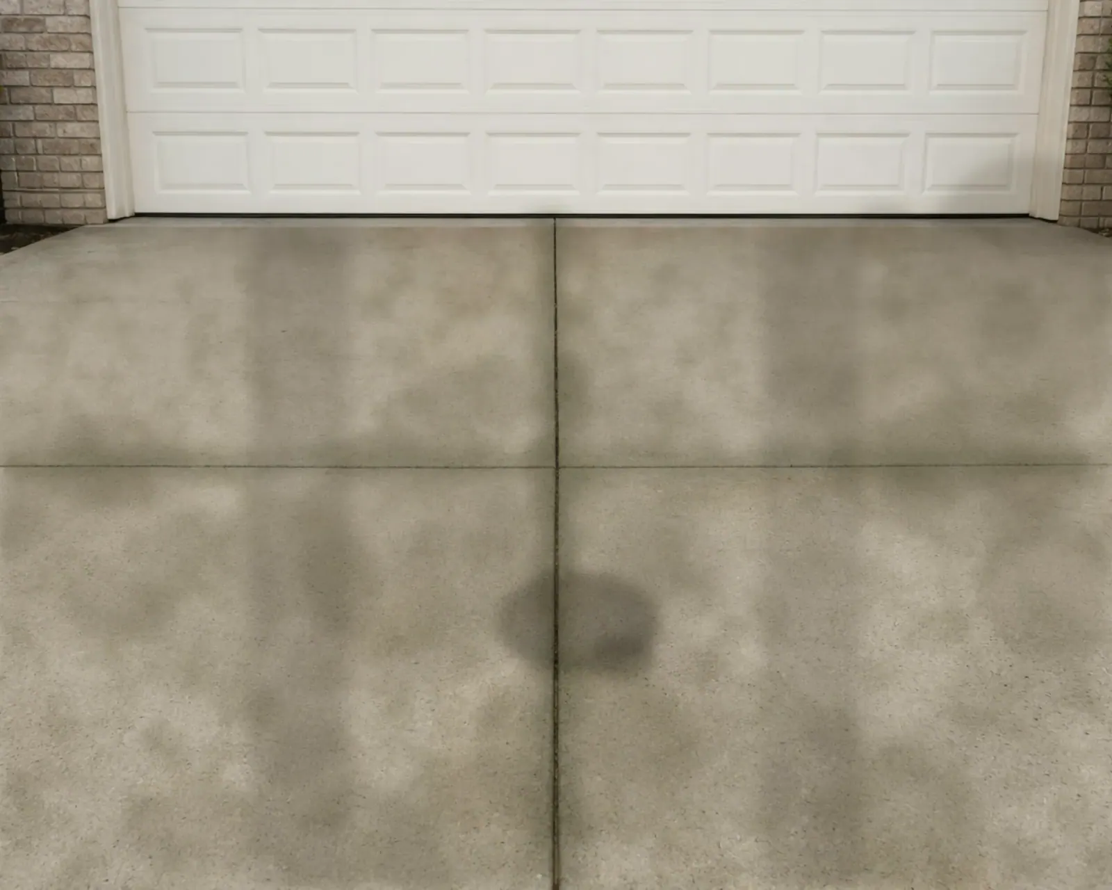 The same driveway before cleaning, streaked with mildew and tire marks