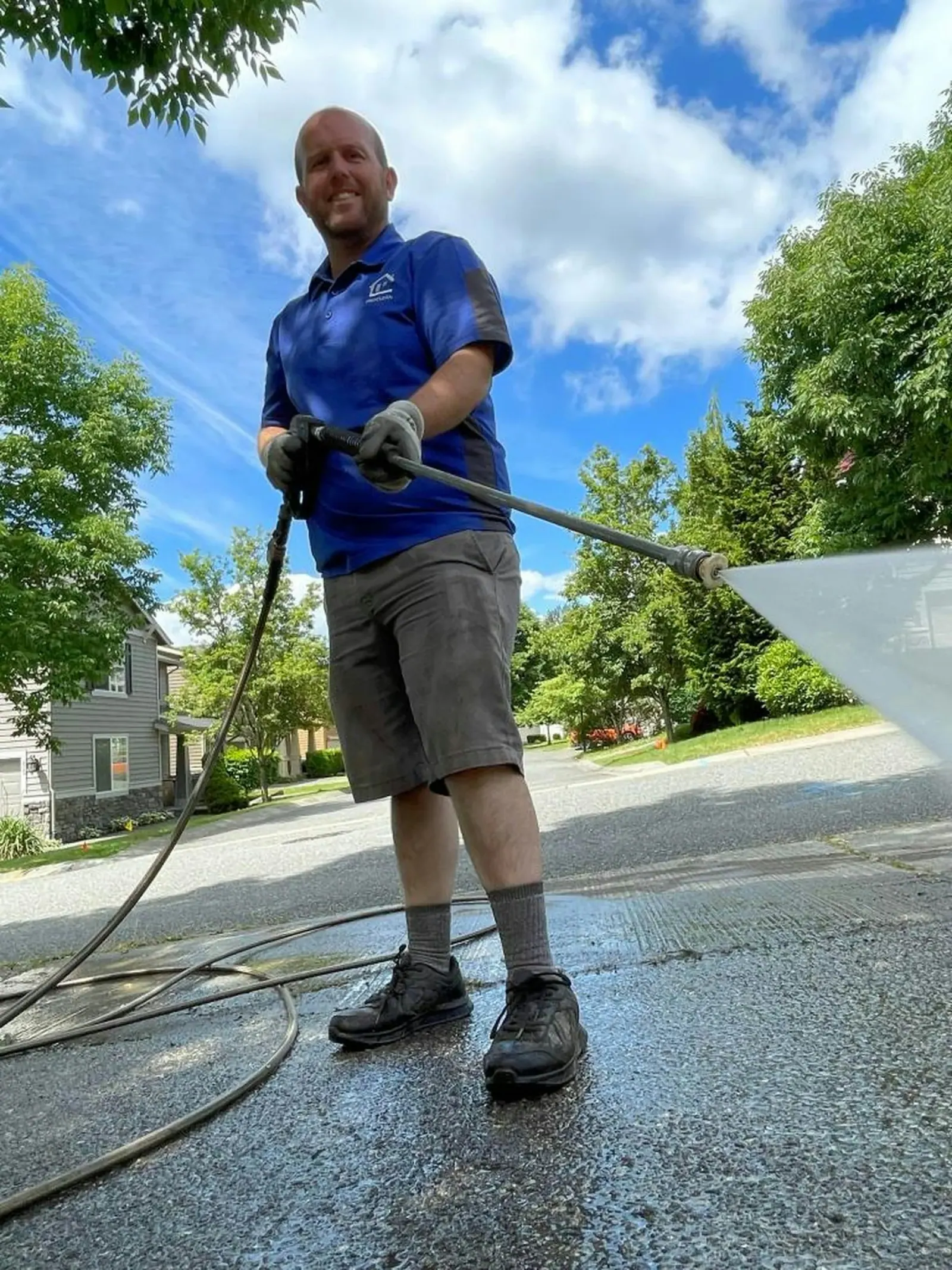 Technician washing a residential driveway with a wand