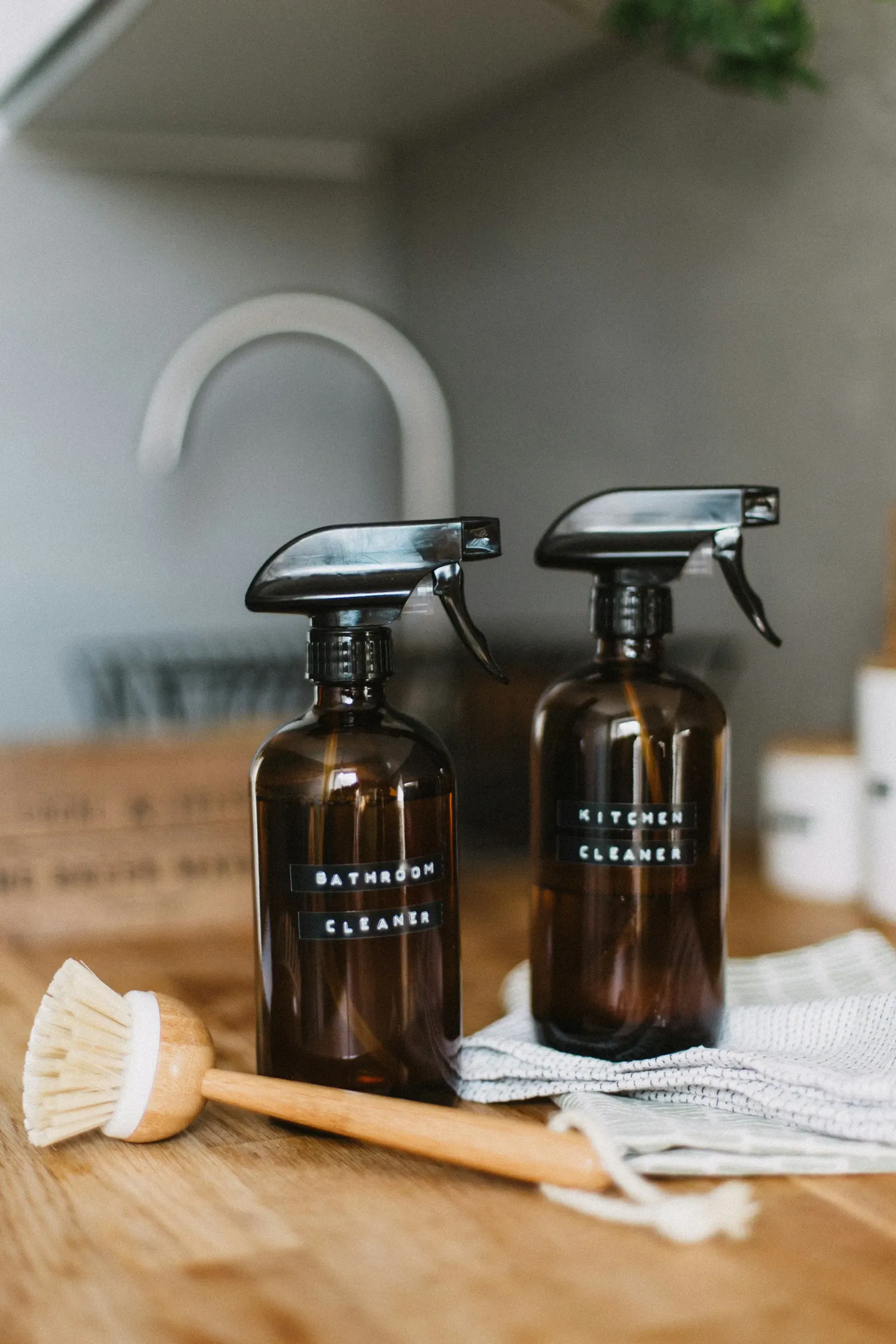 Two amber glass spray bottles labelled for bathroom and kitchen