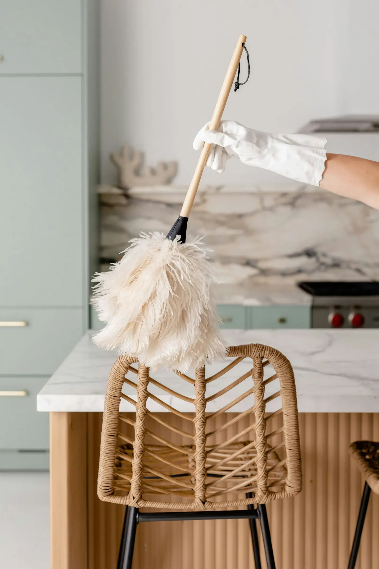 Feather duster sweeping over a marble counter and wicker chair